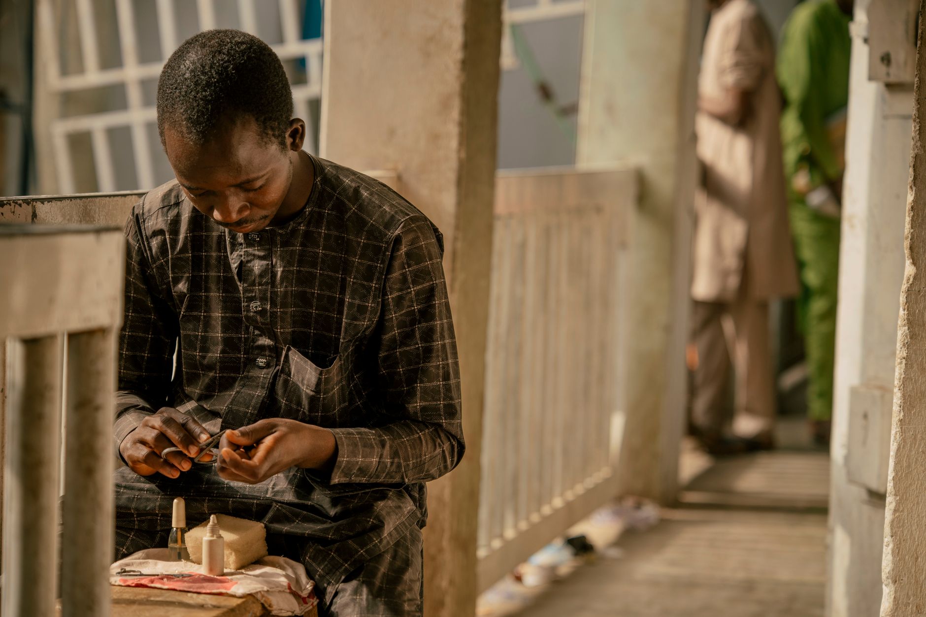 A young artisan focuses on crafting in a Nigerian market setting, showcasing local culture.