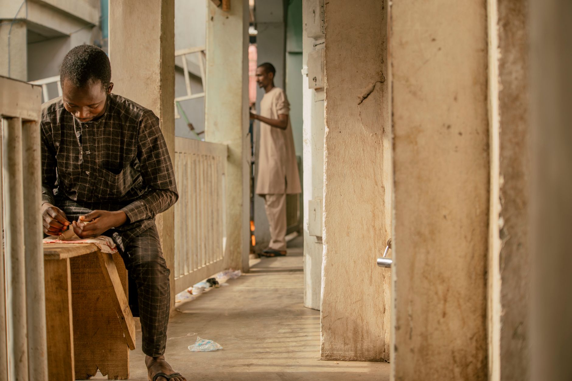 A focused craftsman works in a corridor in Nigeria, showcasing traditional craftsmanship.