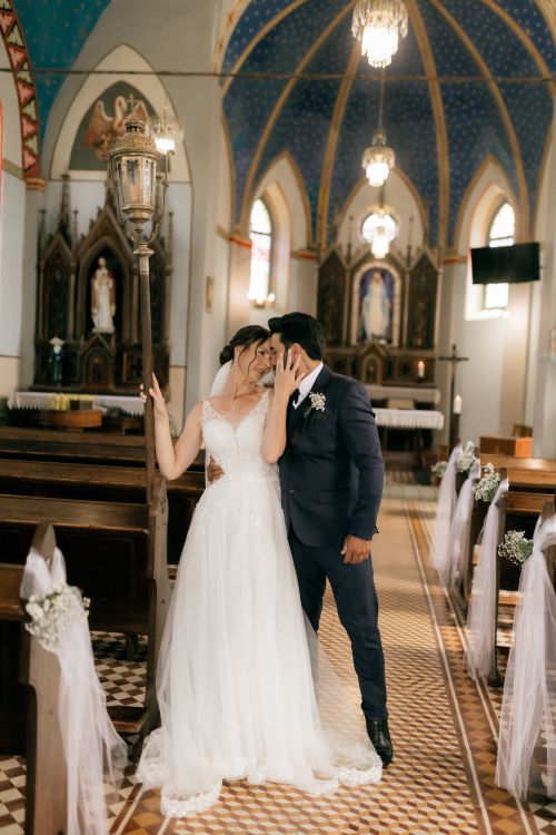 Free Bride and groom share a tender moment in a stunningly decorated church, capturing pure wedding bliss. Stock Photo