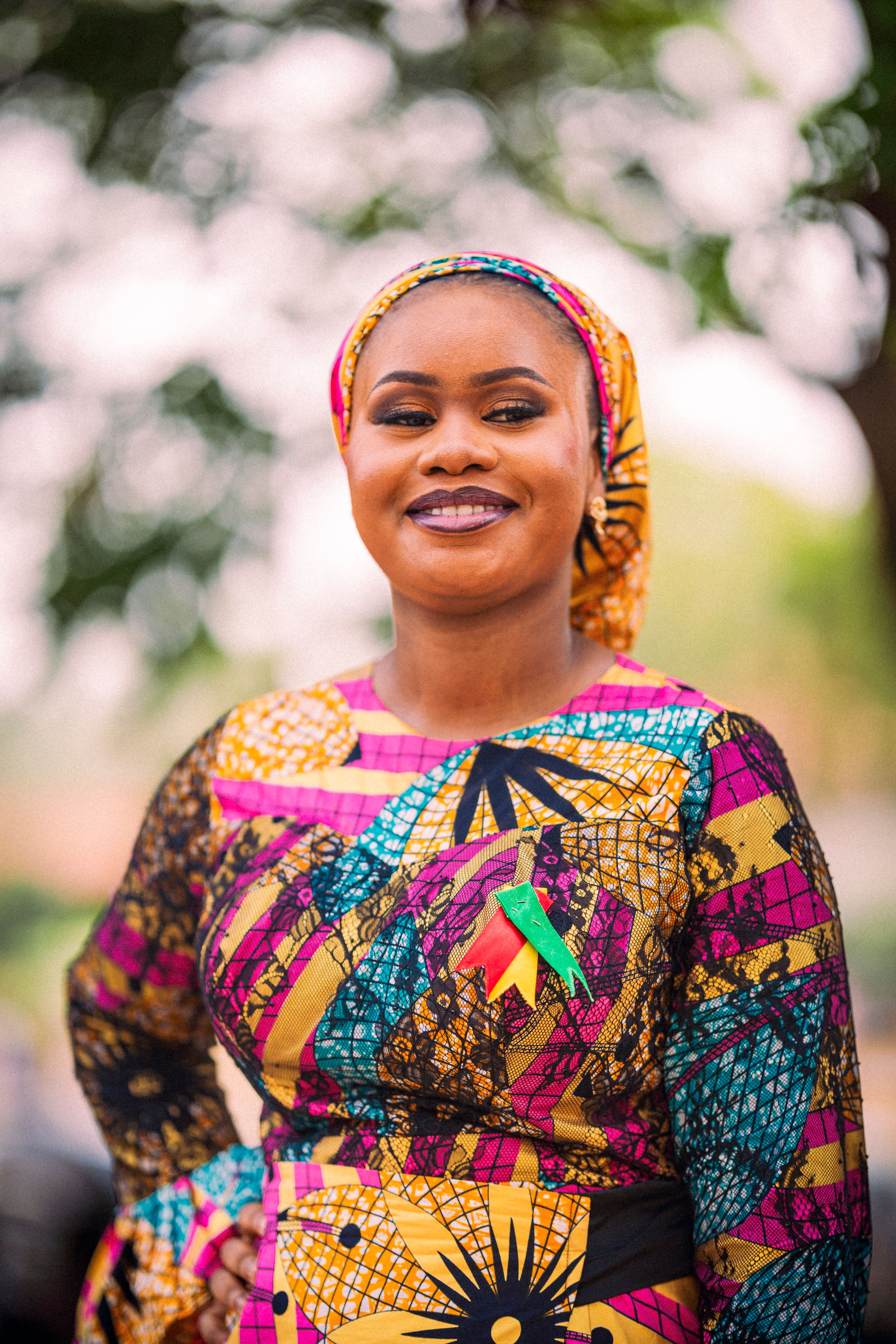 Bright and colorful portrait of a woman in traditional attire, smiling confidently outdoors.