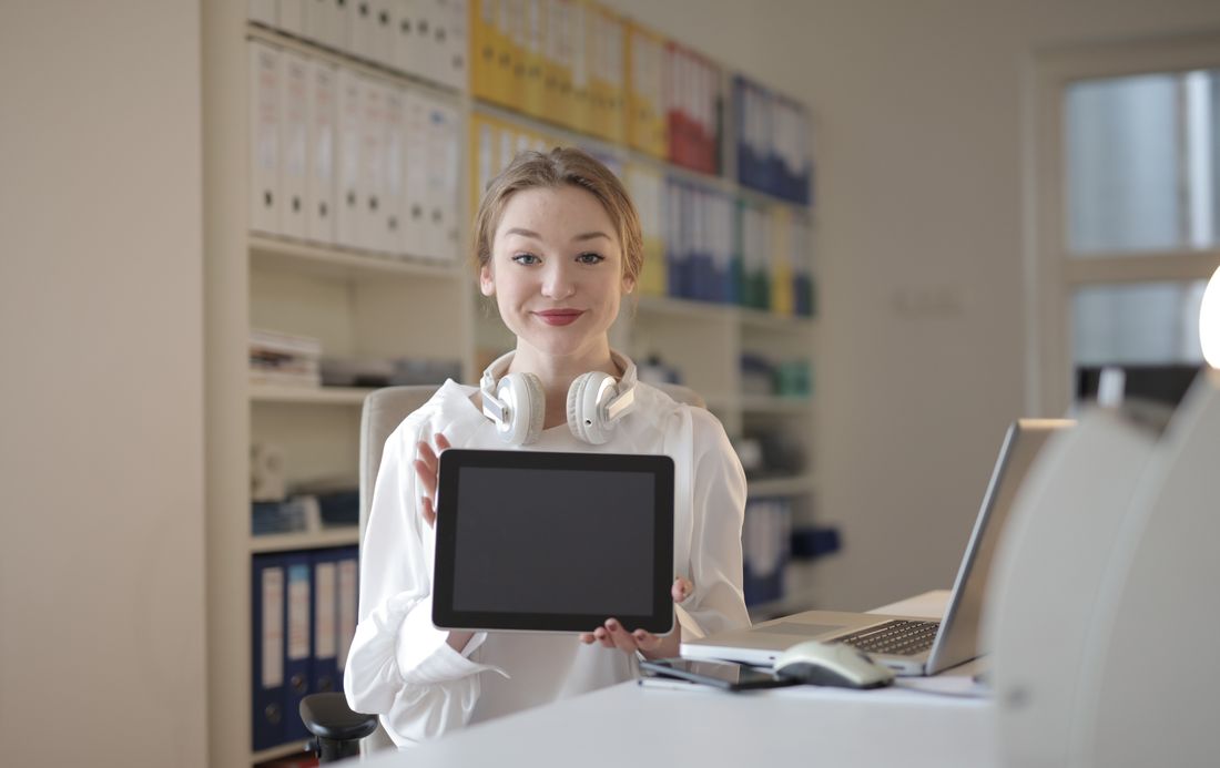 Smiling woman in office holding a tablet