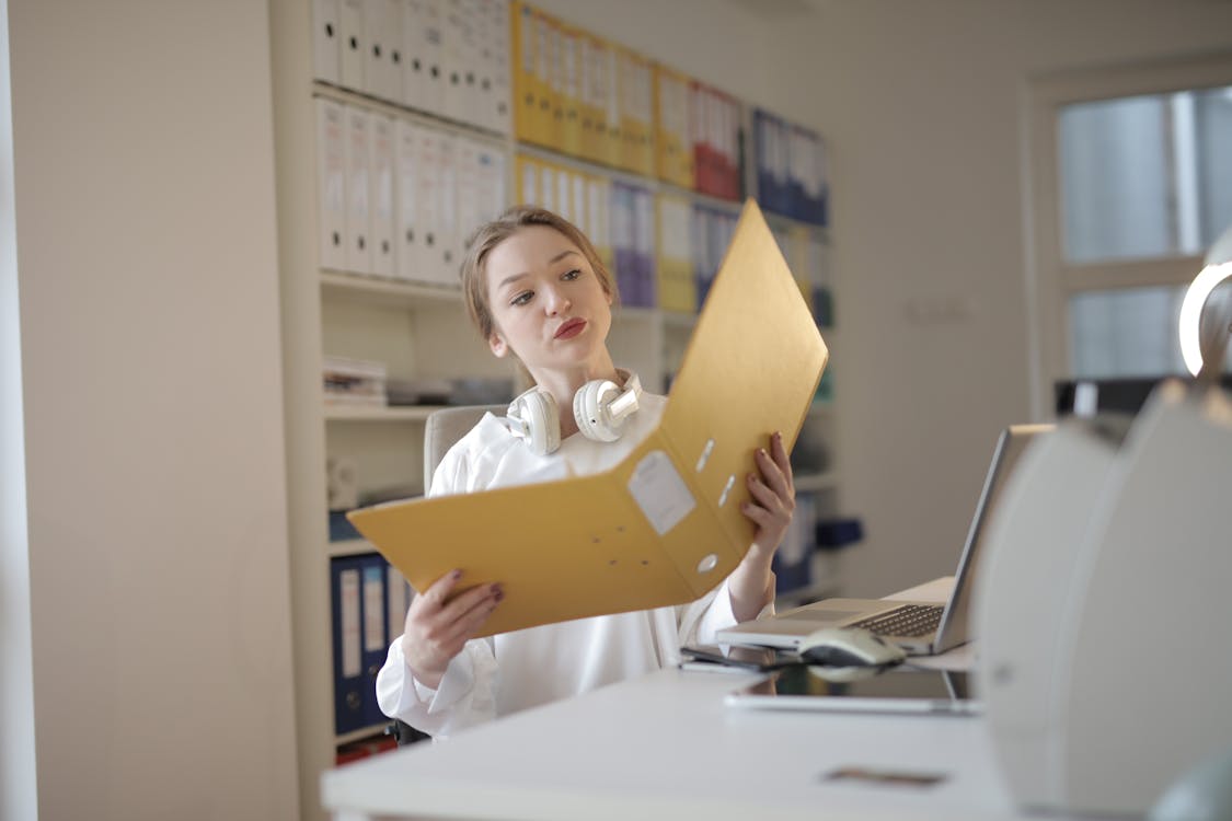 Free Thoughtful female office worker with folder in workplace Stock Photo