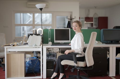 Free Elegant female employee sitting on chair in modern workplace Stock Photo