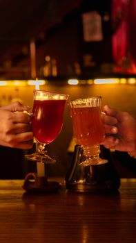 Two people toasting with warm drinks in a cozy, dimly lit bar. Perfect for celebratory themes.