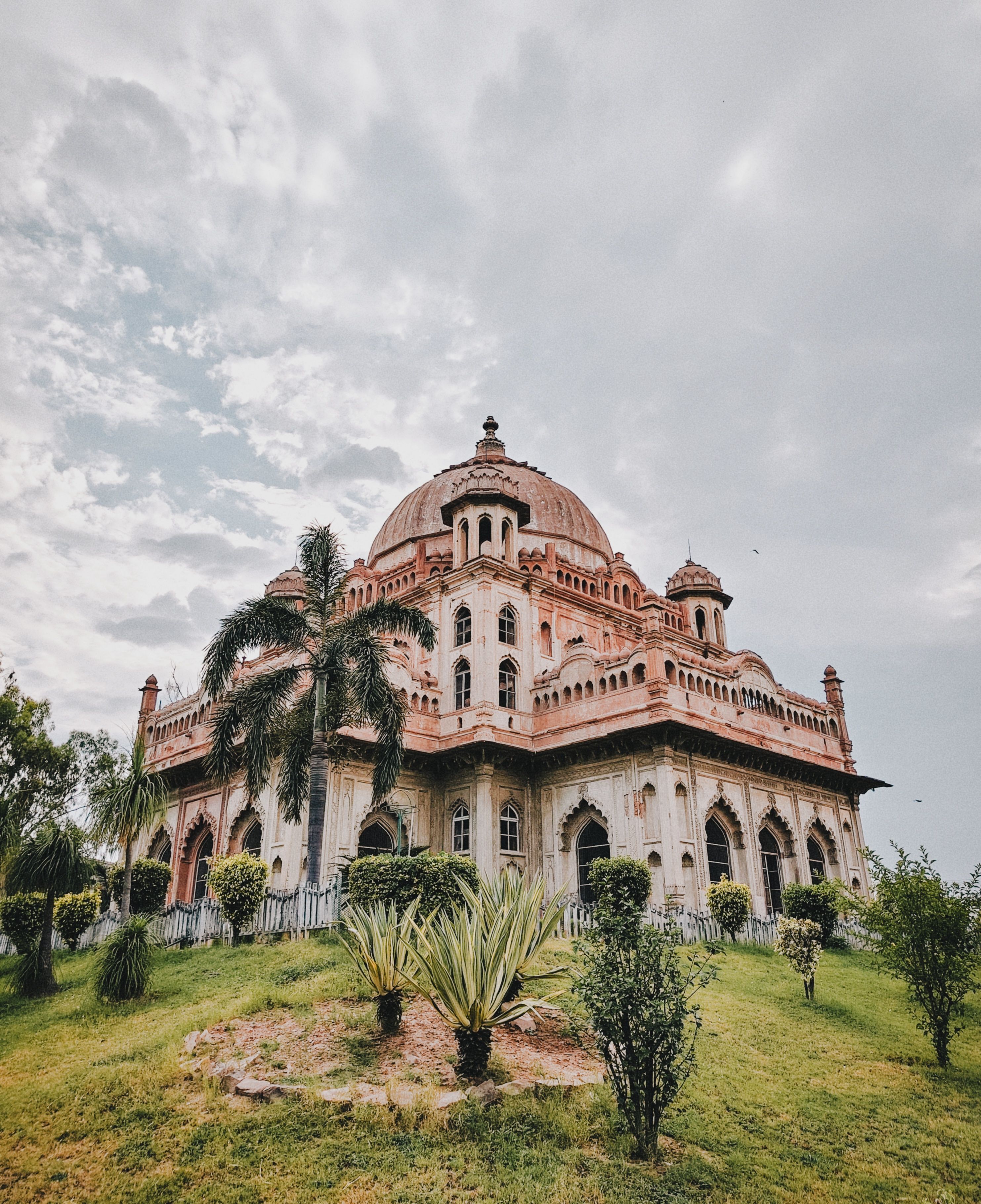 A beautiful dome-shaped architecture set amidst lush greenery with a partly cloudy sky.