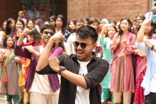 Free Group of young adults dancing joyfully outdoors in a festive atmosphere. Stock Photo