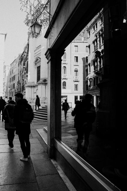 A dynamic black and white street photograph capturing pedestrians walking in a European city.