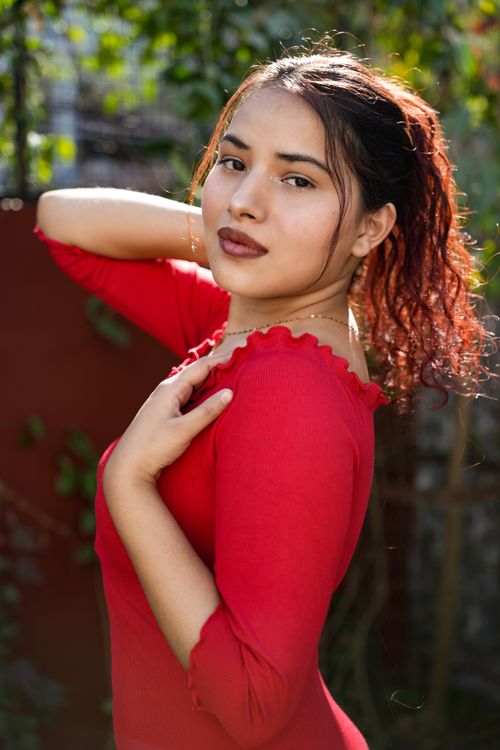Free Glamorous outdoor portrait of a woman wearing a red dress with confident expression. Stock Photo