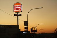 Silhouette of Burger King and McDonald's signs at sunset in Johannesburg.
