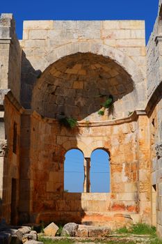Explore ancient Roman ruins featuring a massive arch and vaulted ceiling under clear blue skies.