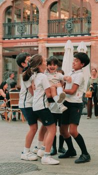 A group of kids enjoying a playful moment in a sunny plaza in Seville, Spain.