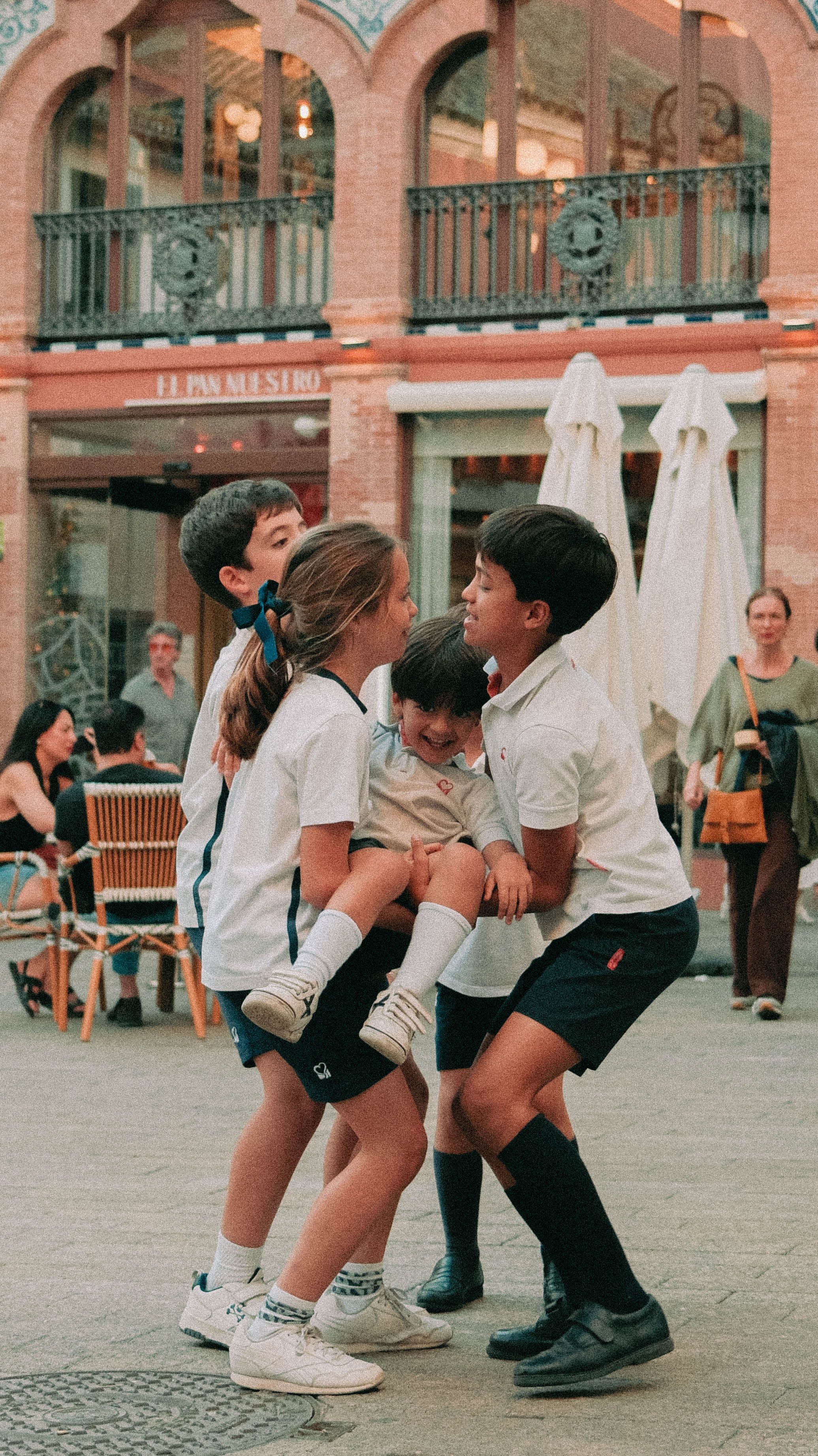 Fotomural Un grupo de niños disfruta de momentos de juego en una pintoresca plaza de Sevilla, España.
