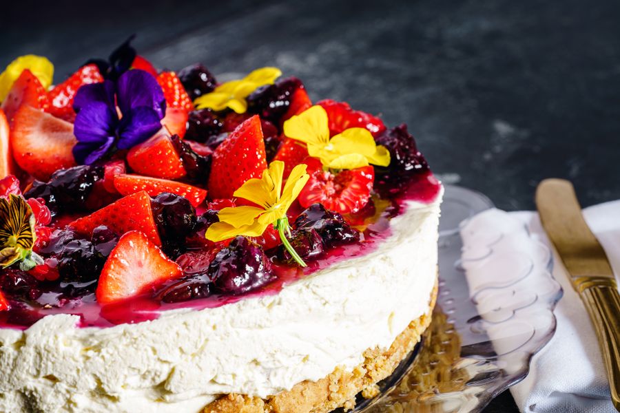 White frosted celebration cake topped with fresh strawberries and berries