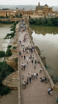 Aerial view of people walking on the historic Roman Bridge in Córdoba, Spain.
