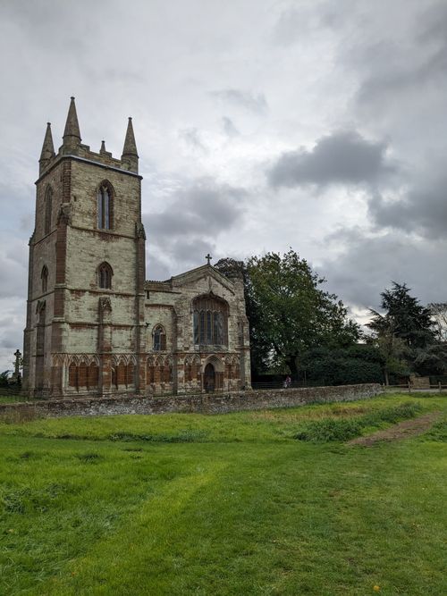 Free Historic stone church with gothic architecture under a cloudy sky in a rural setting. Stock Photo