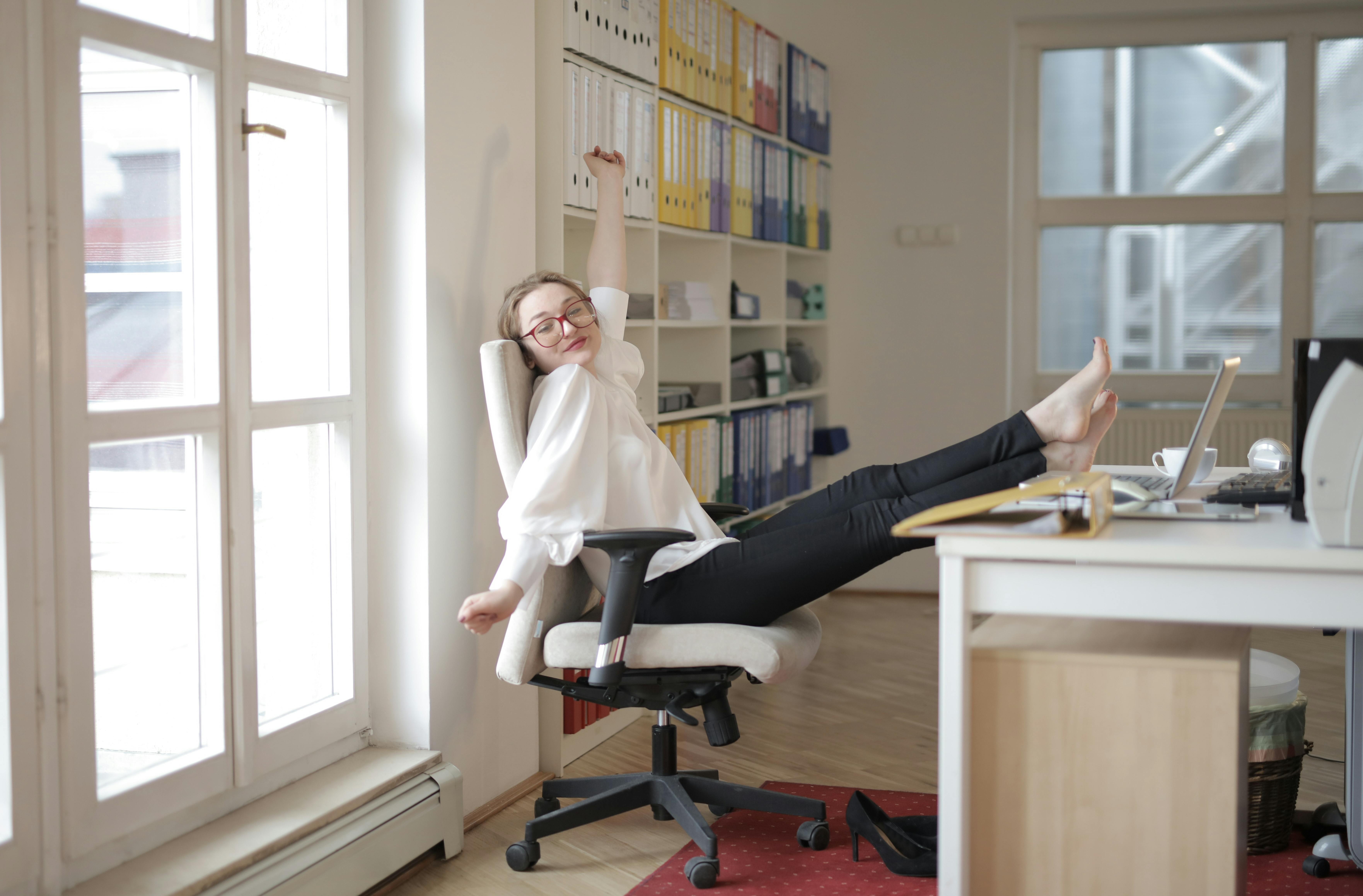 dreamy female employee relaxing with feet on table in office