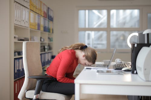 Donna In Camicia A Maniche Lunghe Rossa Che Si Siede Sulla Sedia Mentre Si Appoggia Sul Computer Portatile