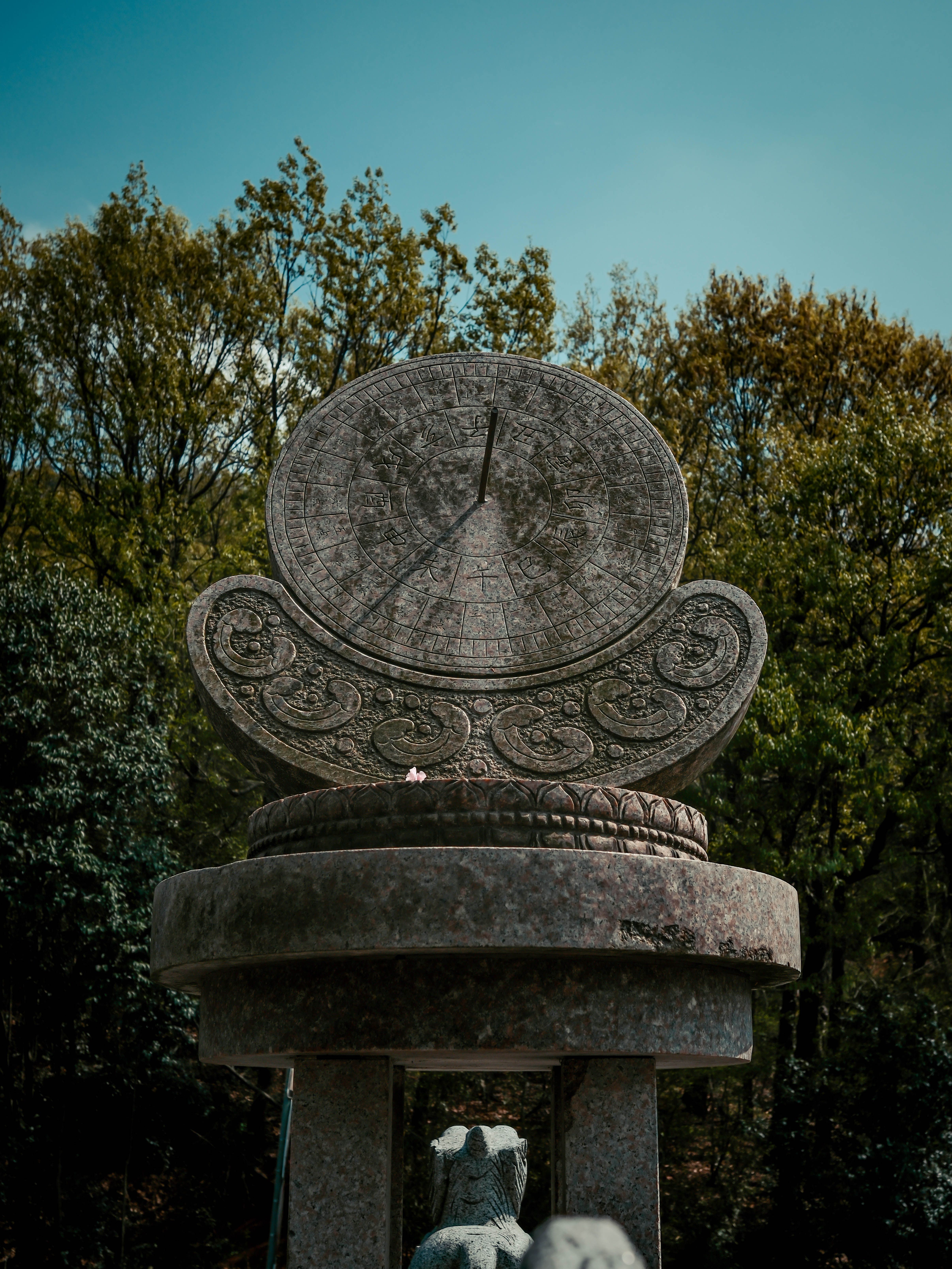 A beautifully carved stone sundial set amidst lush greenery, perfect for time and history themes.
