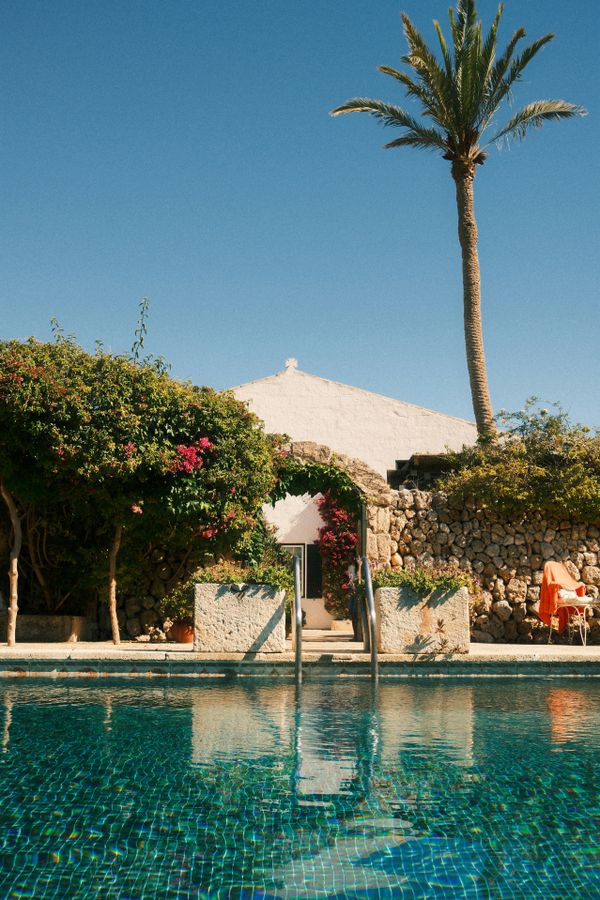Sunlit stone house with a pool and palm tree, by Nuri Askerhan on Pexels