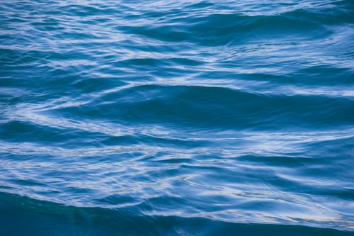 Free Tranquil blue ocean waves creating a mesmerizing abstract pattern, capturing the serene beauty of nature. Stock Photo