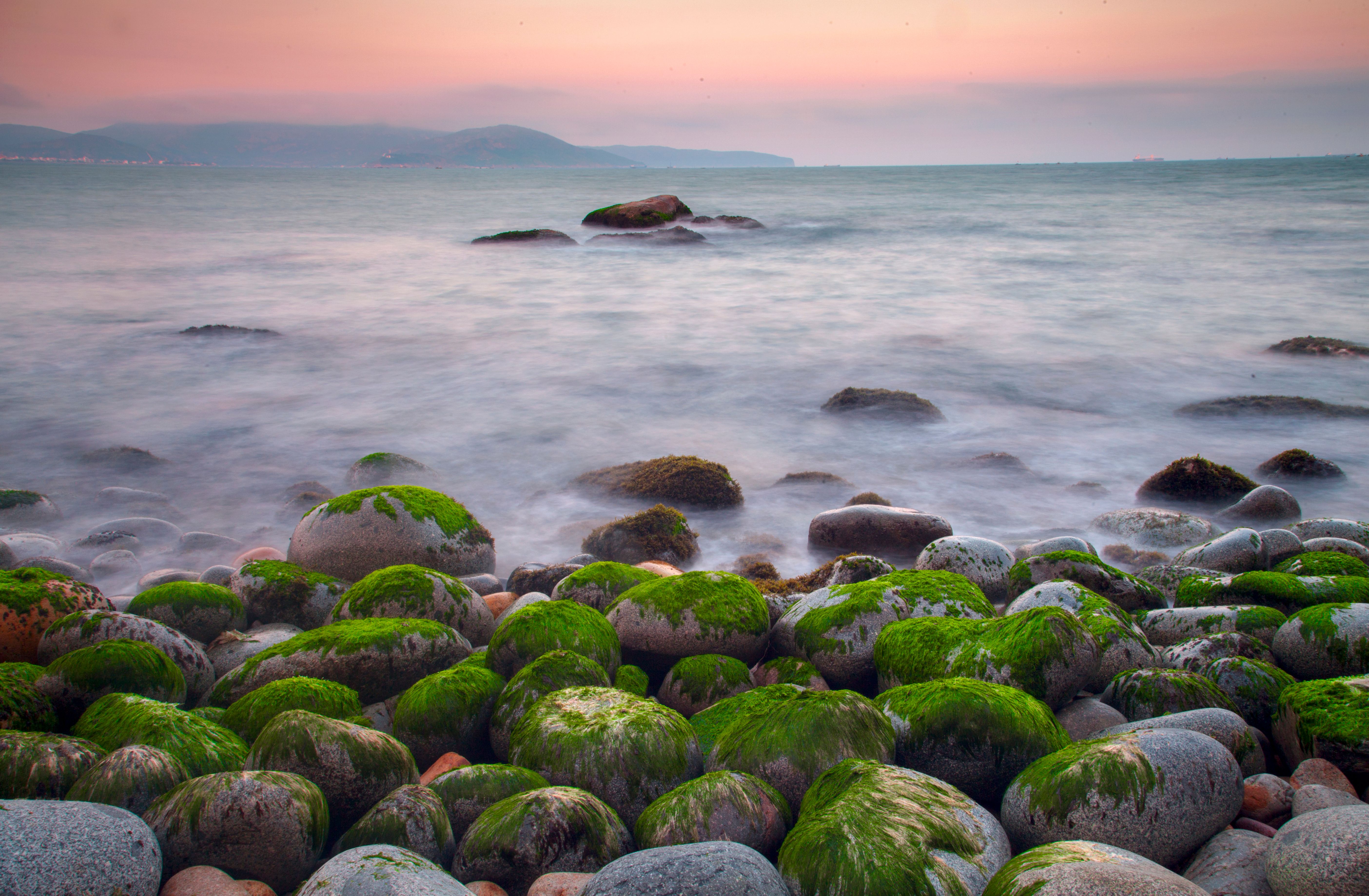 Peaceful ocean scene with mossy rocks and tranquil waves, perfect for meditation and relaxation themes.
