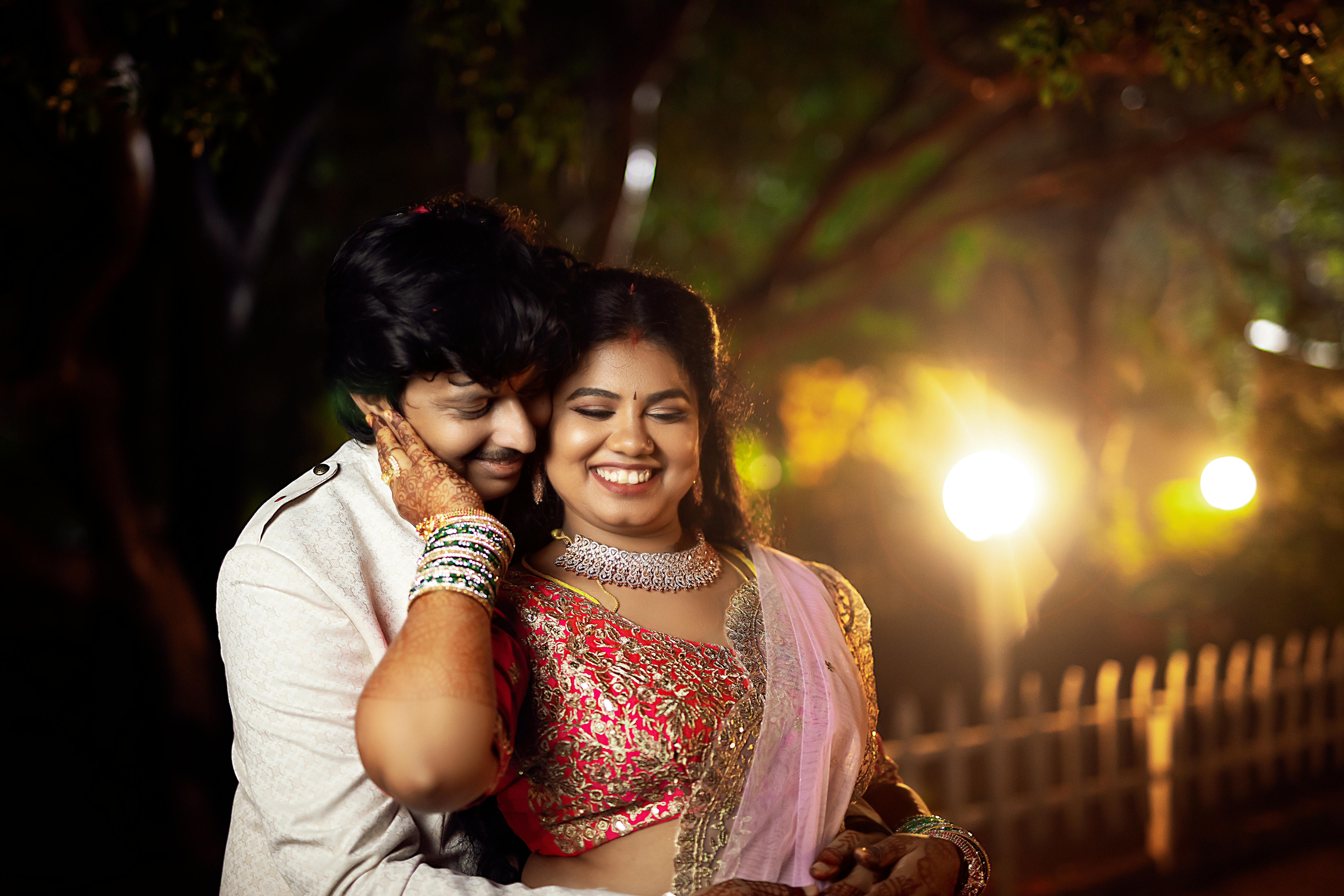 Happy Indian couple embracing outdoors at night in Hyderabad with festive attire.