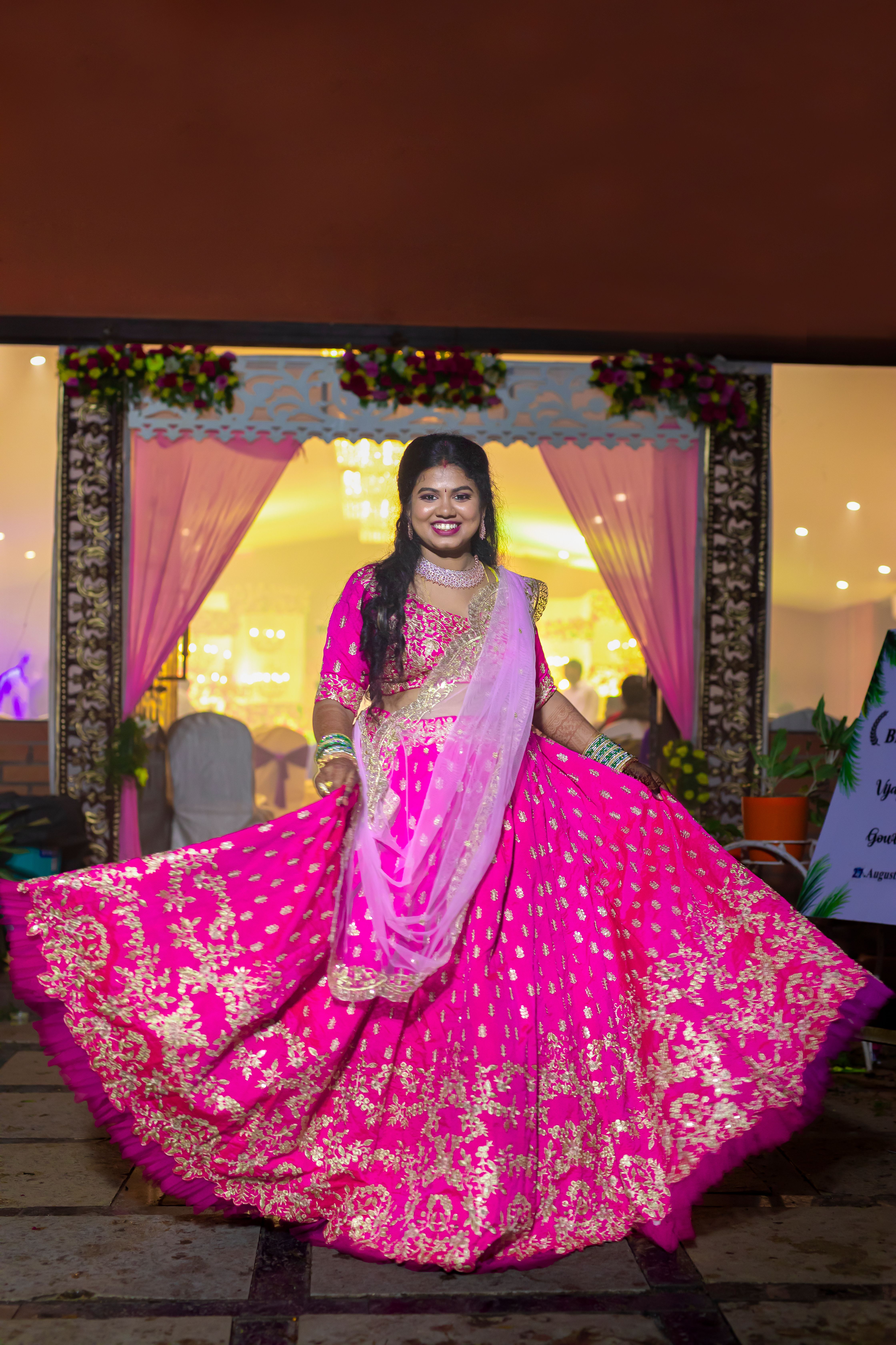 Elegant South Asian bride twirls in a vibrant pink lehenga at a Hyderabad wedding event.