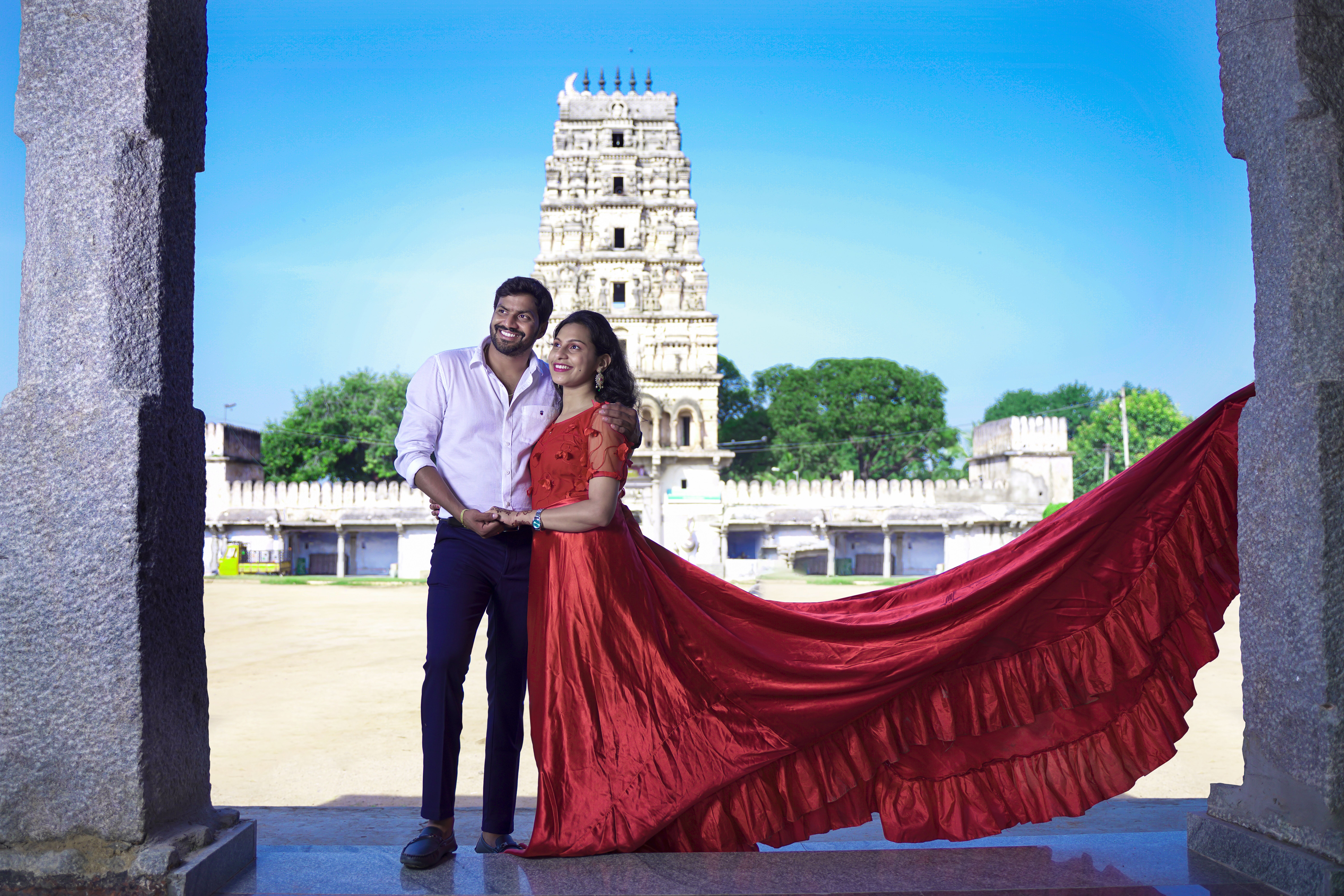 Romantic Indian couple poses in front of historic temple in Hyderabad, dressed elegantly. Vibrant and joyful scene.