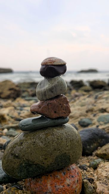 Fotomural Piedras apiladas en una playa serena, que representan armonía y equilibrio en la naturaleza.