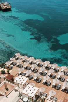 Aerial shot of a coastal resort with sun umbrellas overlooking clear blue waters.