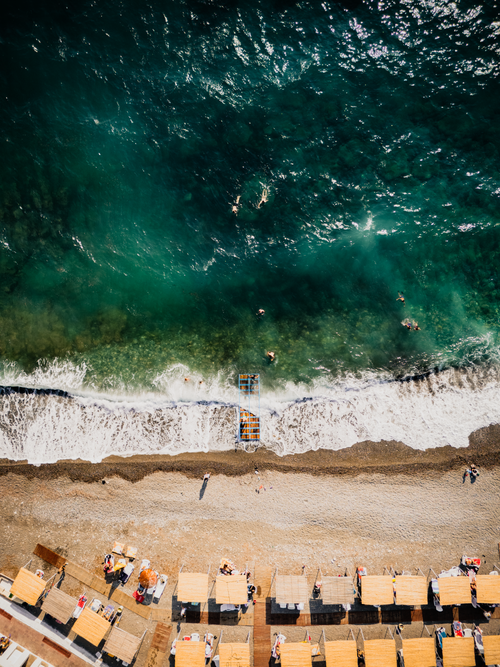 Free Aerial view of beach cabanas and turquoise sea waves. Perfect for travel and lifestyle themes. Stock Photo