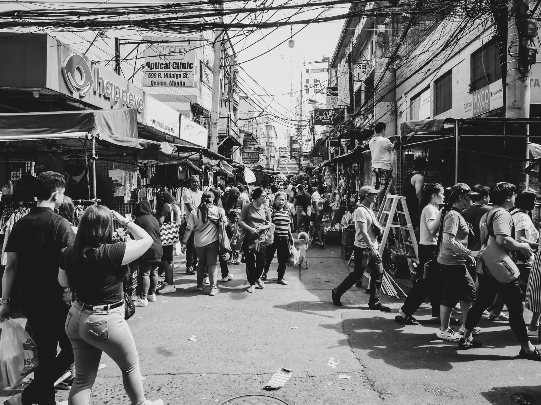 A rural Philippine market crowd watching a cockfighting match beside wooden stalls
