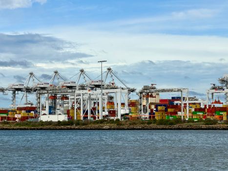 View of a bustling container terminal in Melbourne, showcasing cranes and containers along the waterfront.