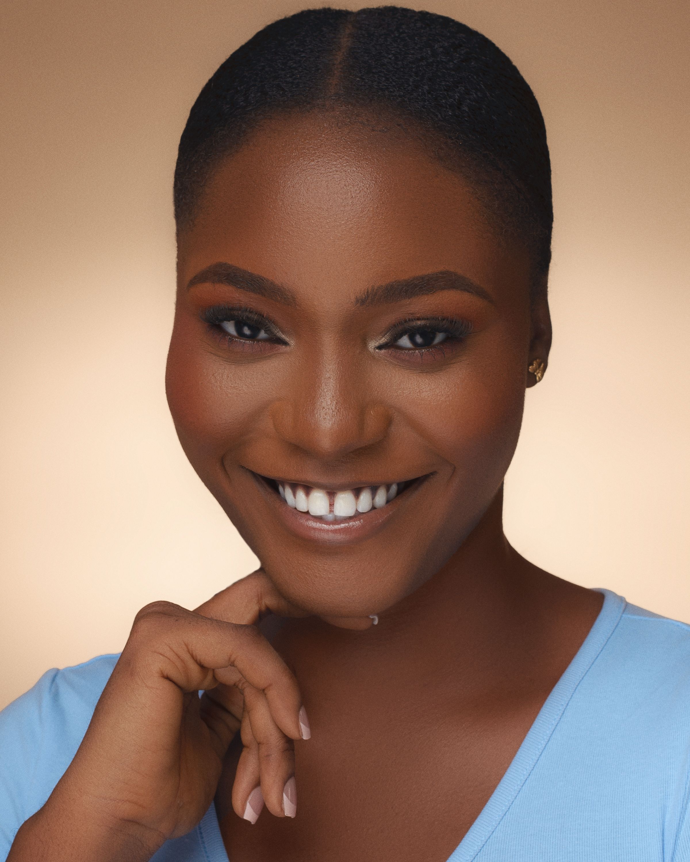 Close-up portrait of a smiling woman against a warm background.