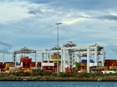 A vibrant image of an automated container terminal at Port Melbourne, Victoria, showcasing industrial freight handling.