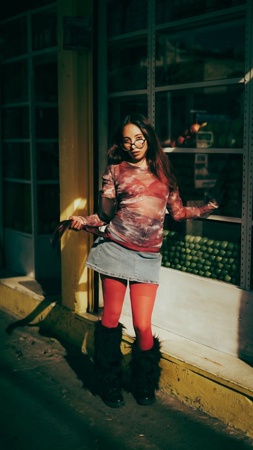Free Stylish woman in bright attire poses confidently on a sunlit urban street. Stock Photo