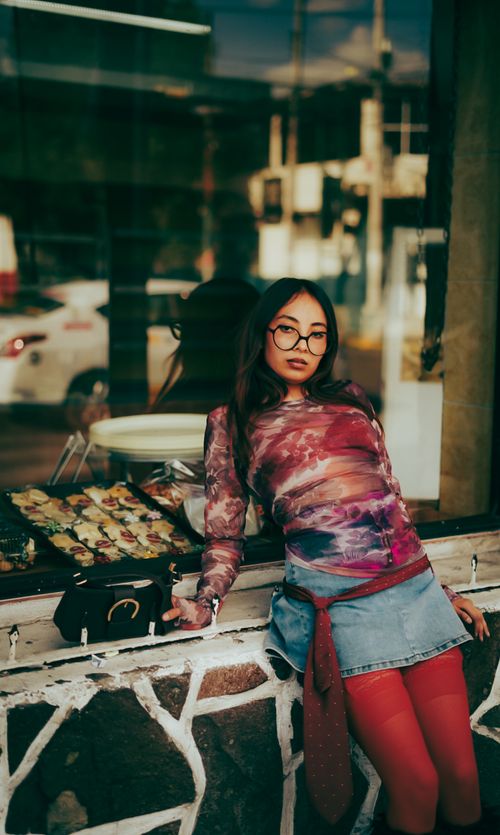 Free Fashionable woman in a vibrant outfit posing against a city storefront with modern urban vibes. Stock Photo