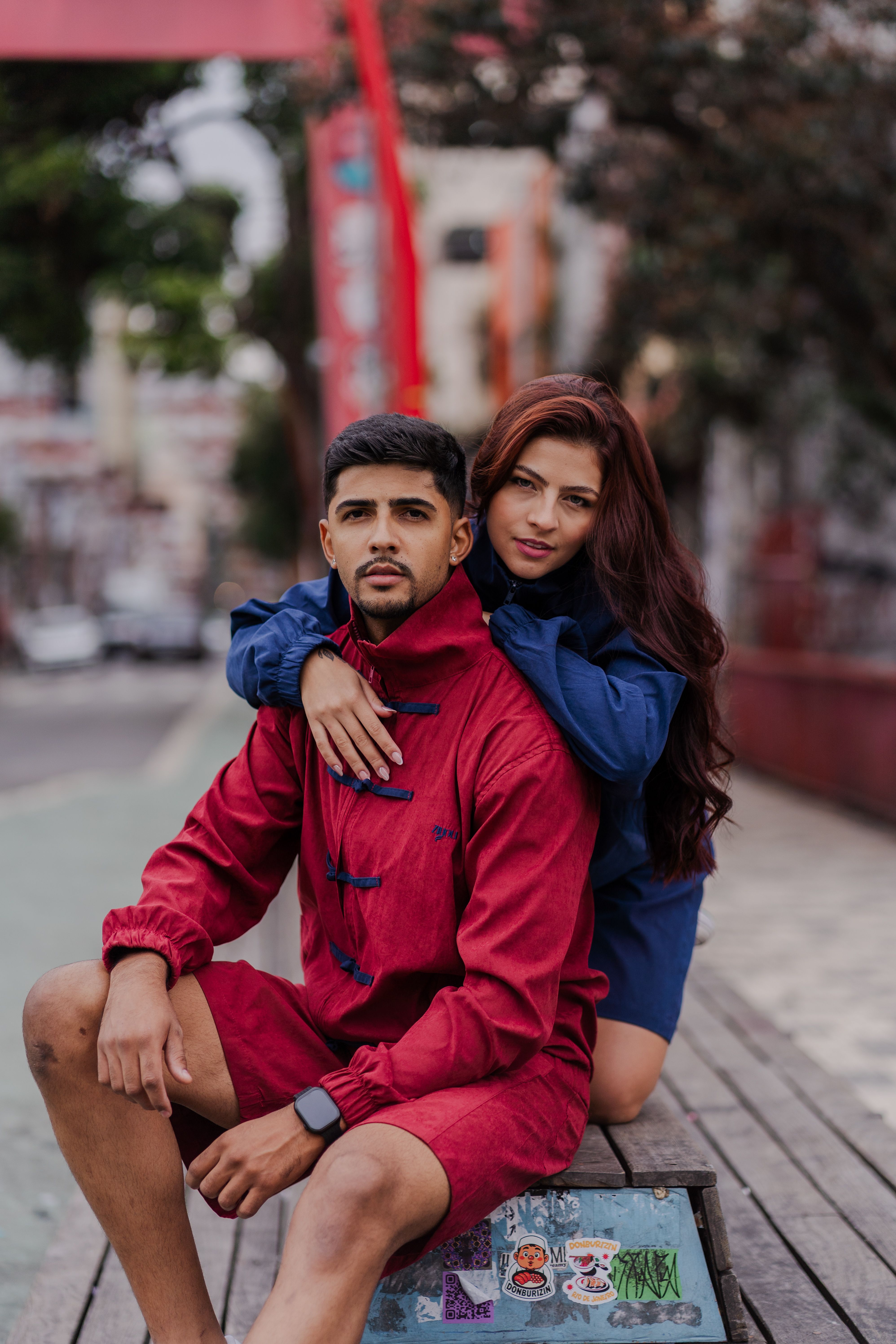 Young couple in stylish outfits posing confidently in an urban setting for a street fashion photoshoot.