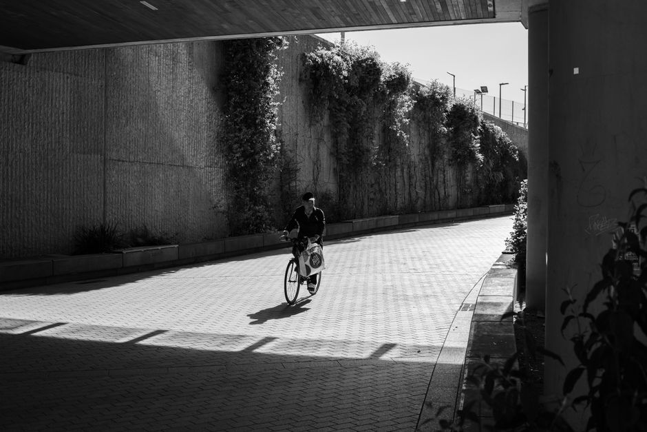 Black and white photo of a cyclist under an urban bridge in Dublin, Ireland.