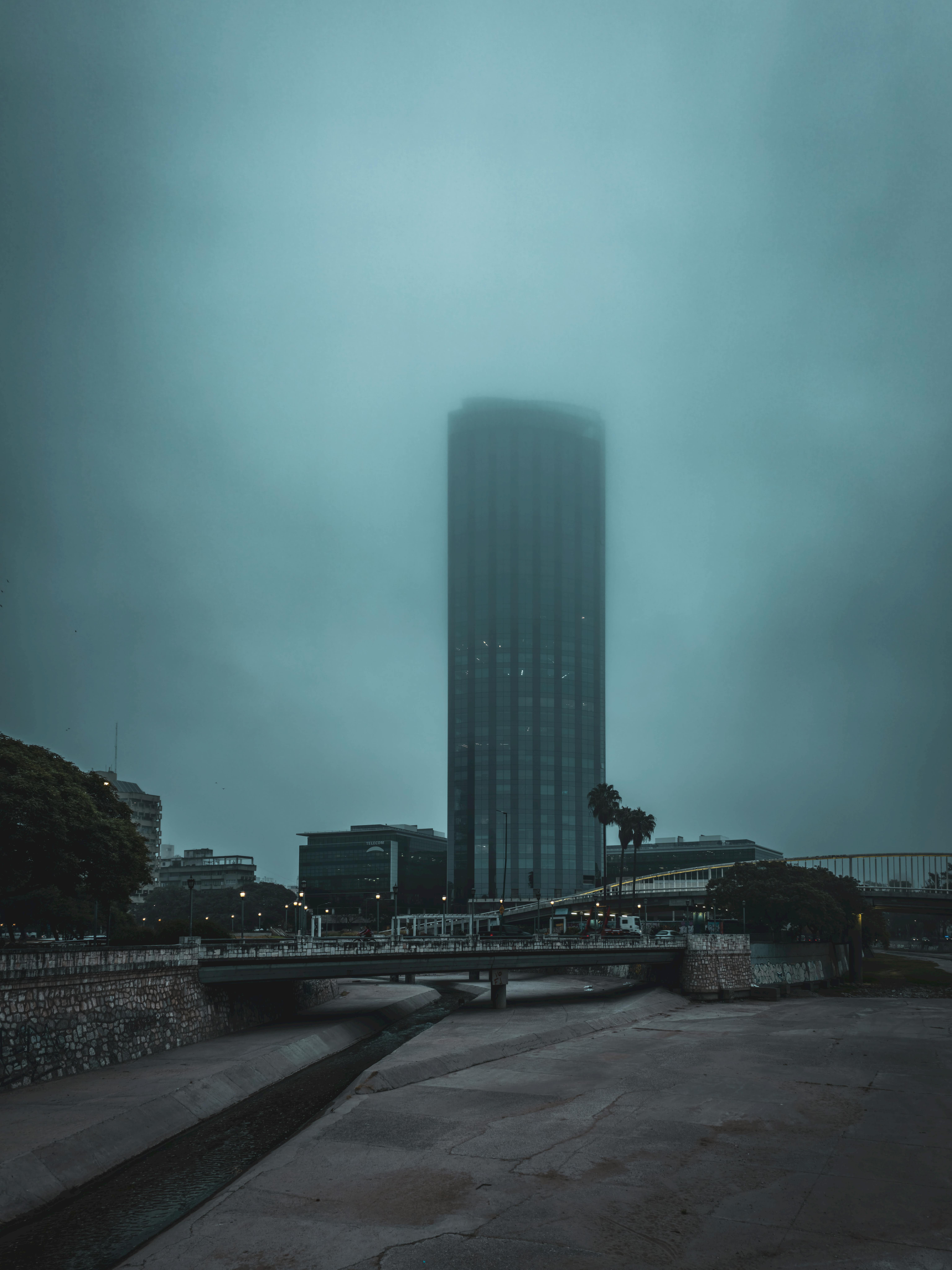 A misty cityscape featuring a towering skyscraper shrouded in fog, offering a dramatic and atmospheric view.