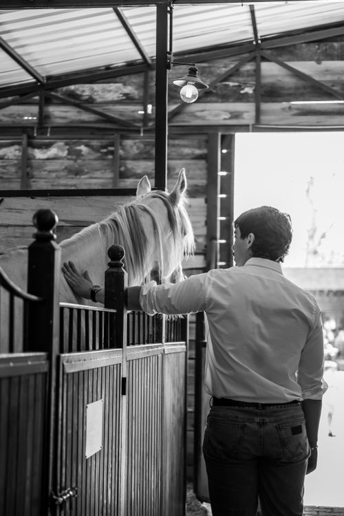 Free Black and white image of a man interacting with a horse in a rustic stable. Stock Photo