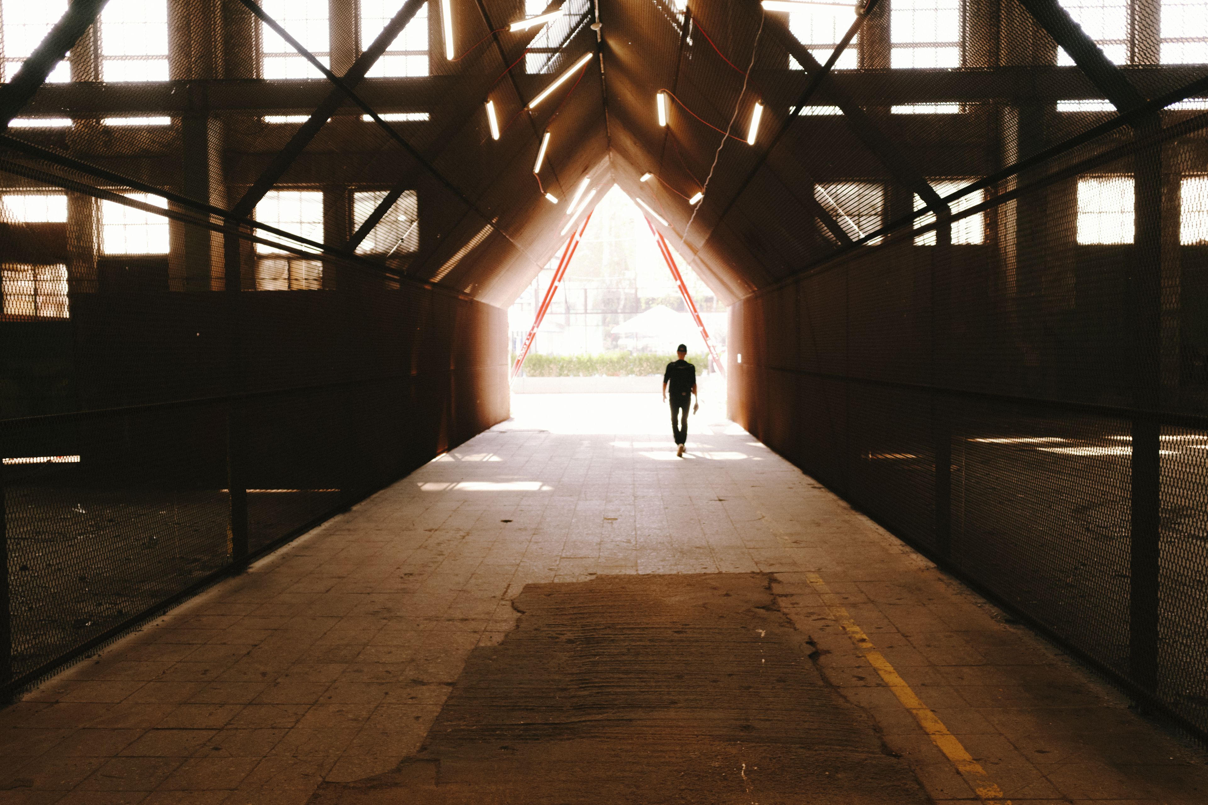Search query: "person walking through foggy tunnel towards bright light"