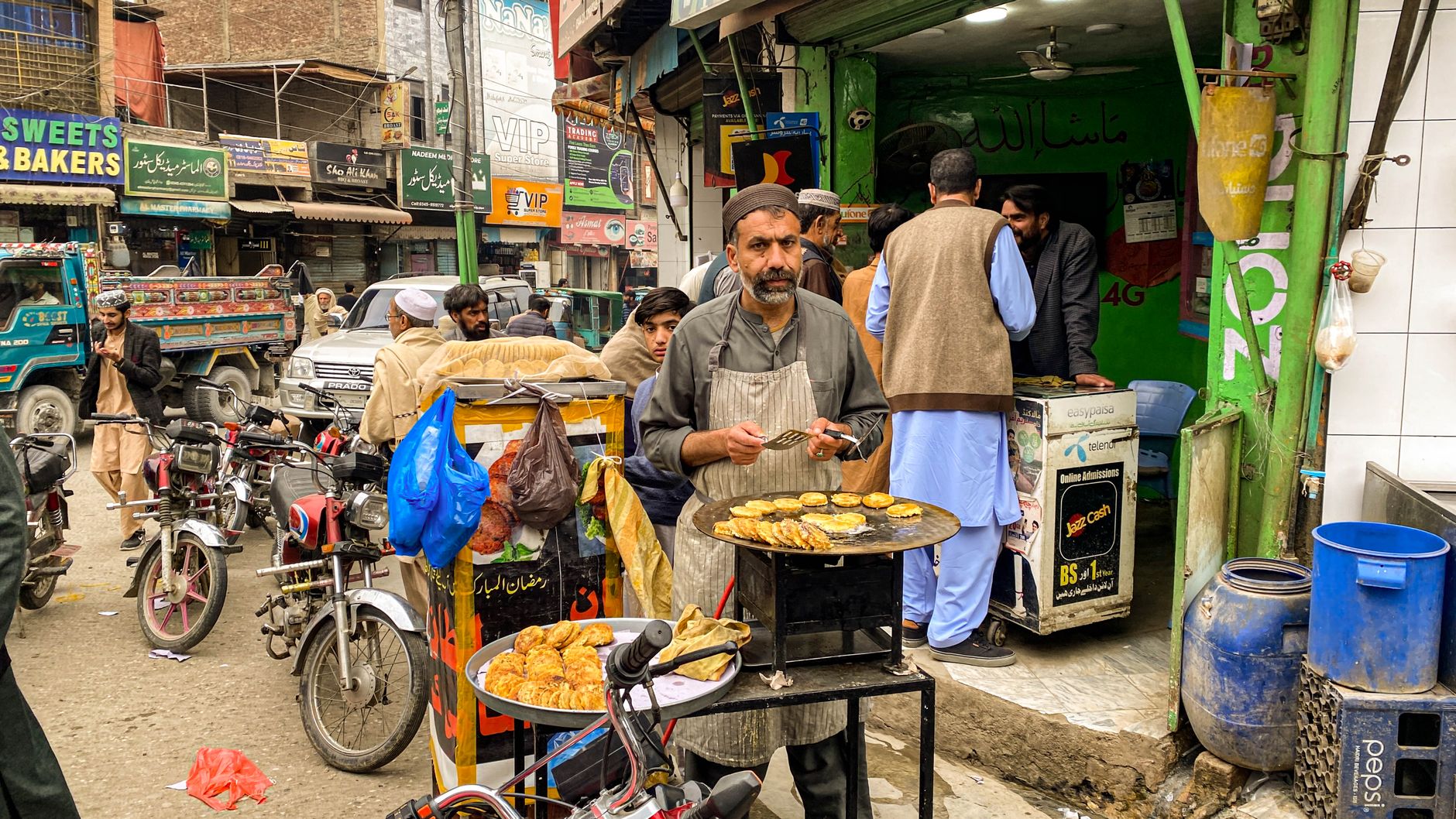 ہاتھ میں پکڑے موبائل پر کارڈ گیم ایپ، ساتھ محفوظ پاس ورڈ اور تصدیقی کوڈ دکھاتا لیپ ٹاپ