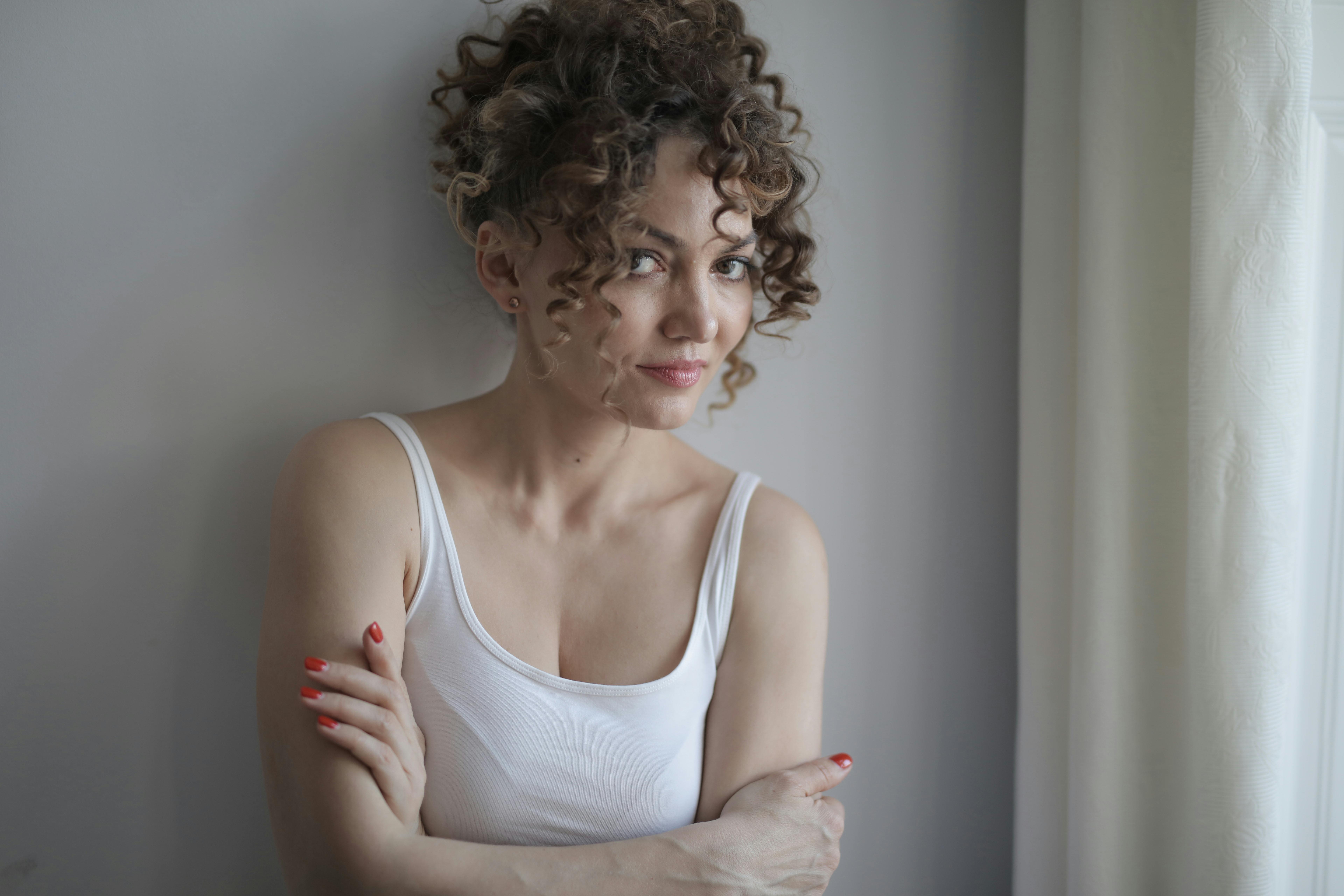 一位卷发微笑的女人在室内自然光下摆着姿势