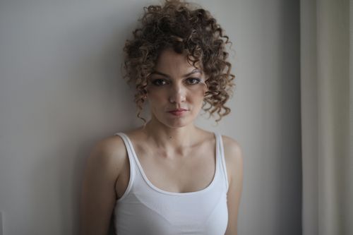 Free Artistic portrait of a woman with curly hair in natural lighting indoors. Stock Photo