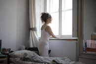 女人在卧室里凝视着窗外，营造出一种平静而宁静的氛围
