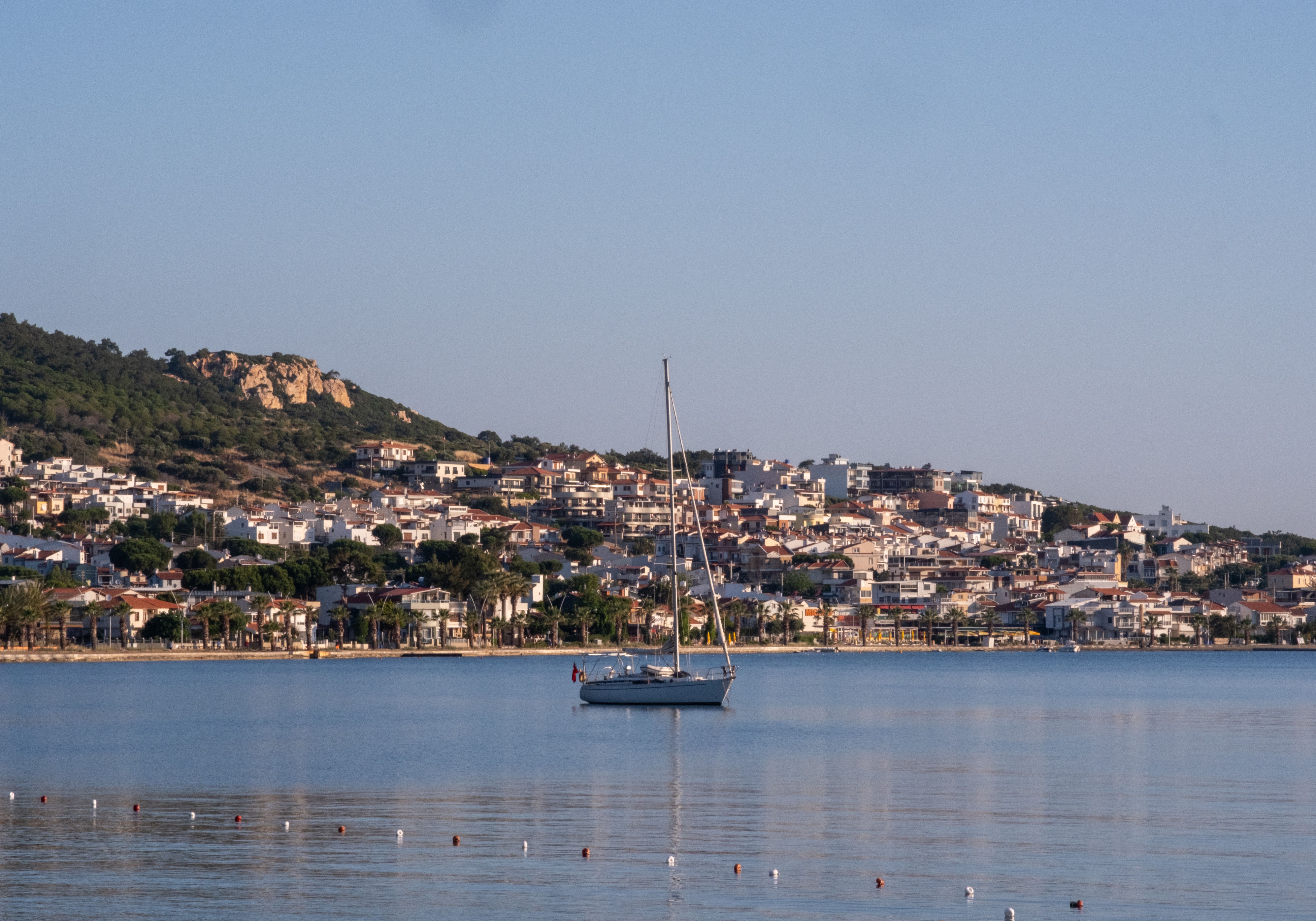 Serene sailboat floating near the charming coastal town of Foça, İzmir, under a clear sky.