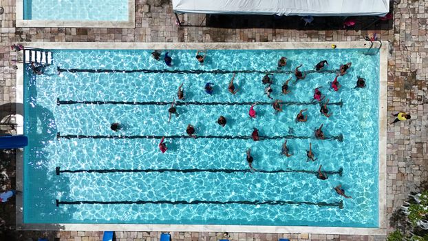 A top-down shot of a swimming pool with people swimming in lanes, located in Moreno, Brazil.
