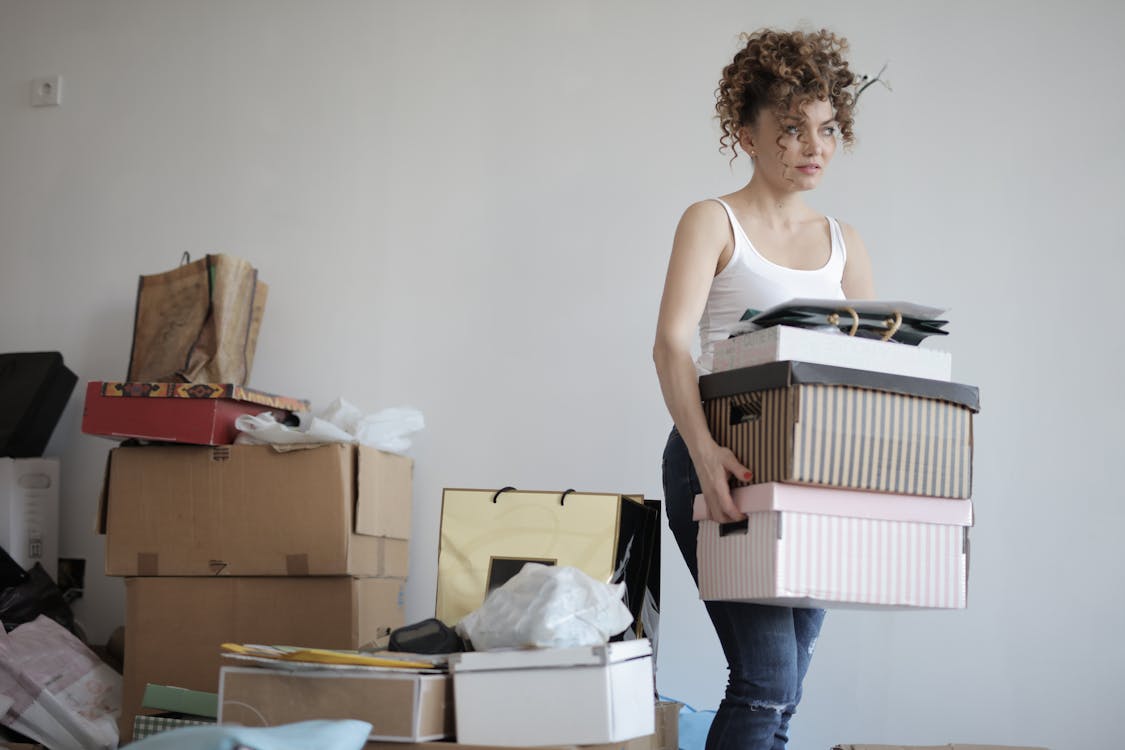 бесплатная Сосредоточенная женщина, несущая стопку картонных коробок для переезда Стоковое фото