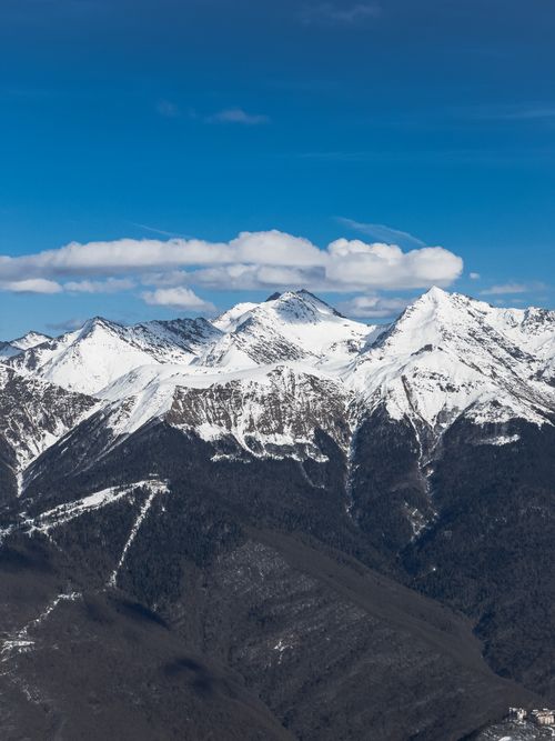 Free A stunning aerial shot captures the majestic snow-covered peaks under a bright blue sky. Stock Photo